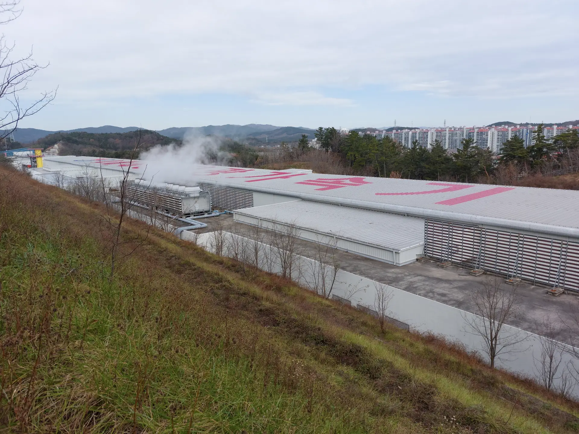 A large accelerator facility seen from the hillside above it.