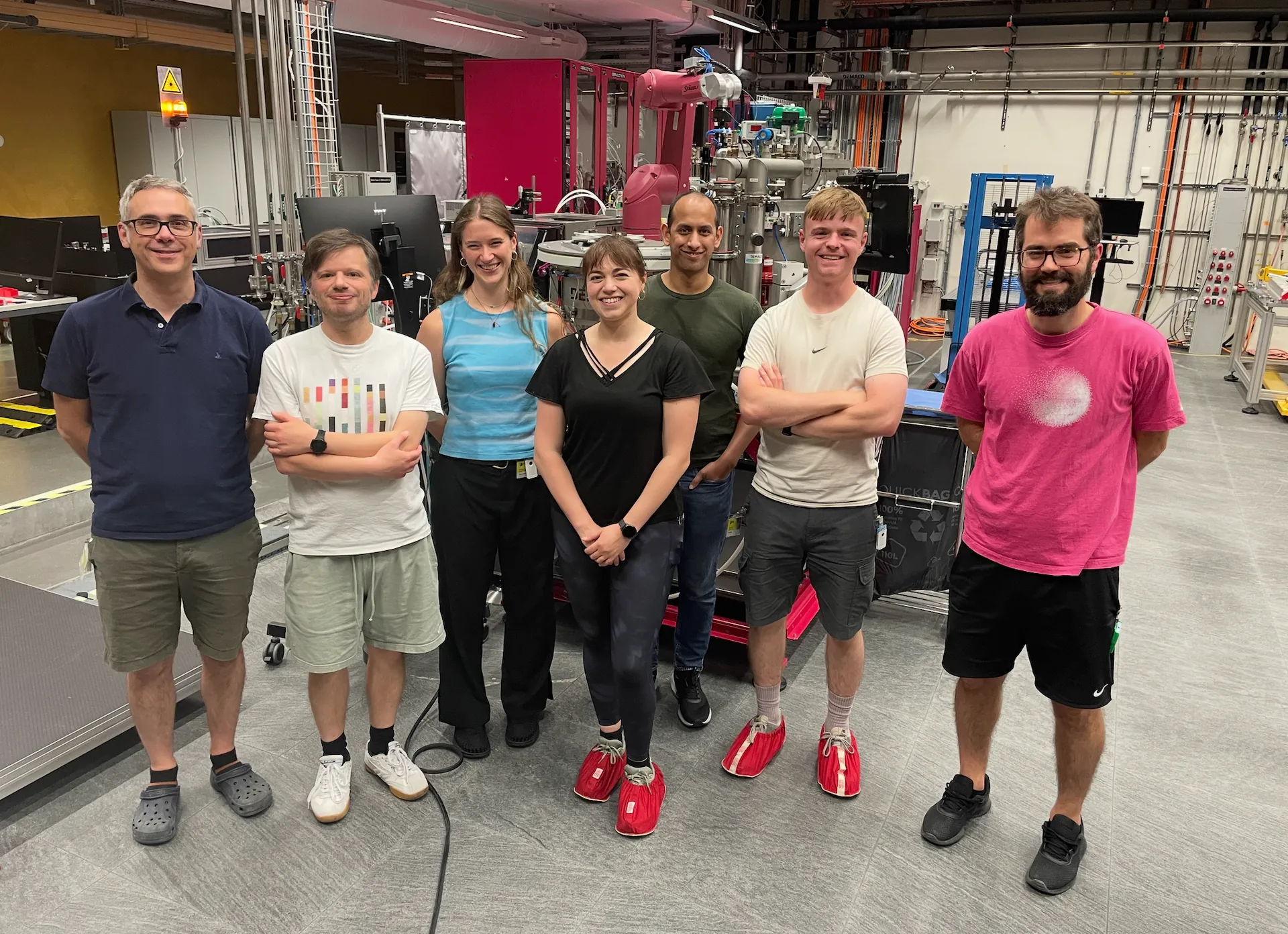 The group standing together in a beamline experimental hall.